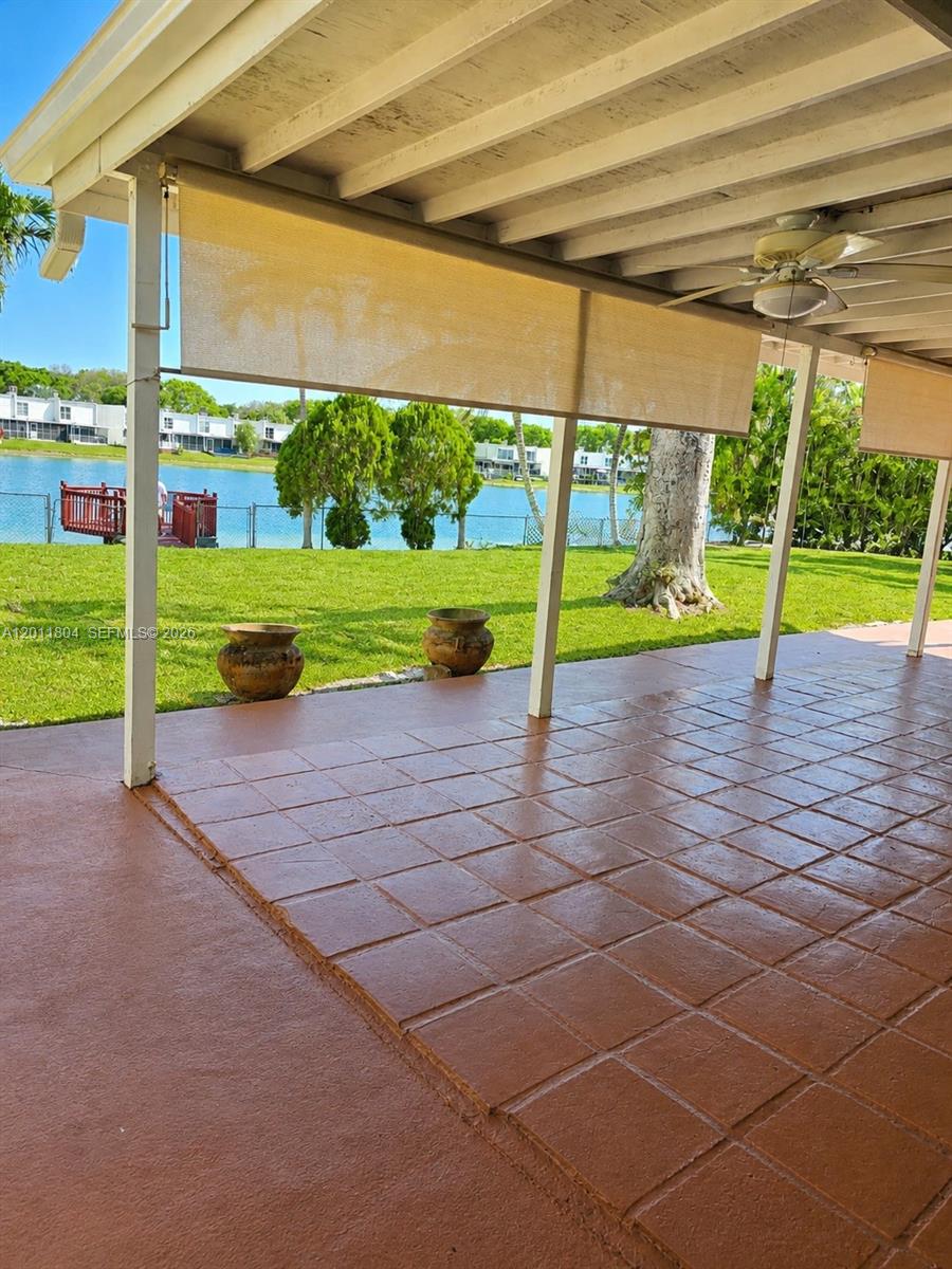 A covered patio with tiled flooring overlooks a grassy lawn and a lake — 14020 SW 83rd St, Miami FL 33183, MIAMI, FL