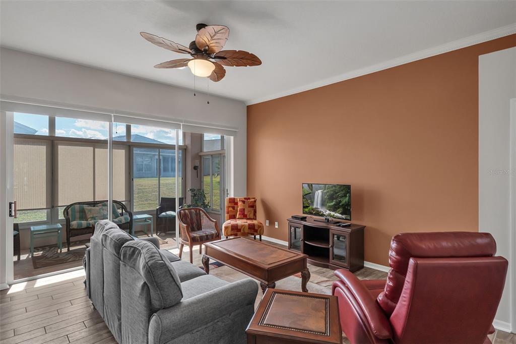 A living room with a terracotta accent wall, gray sofa, red recliner, and ceiling fan — 213 HIGH VISTA DR, DAVENPORT, FL