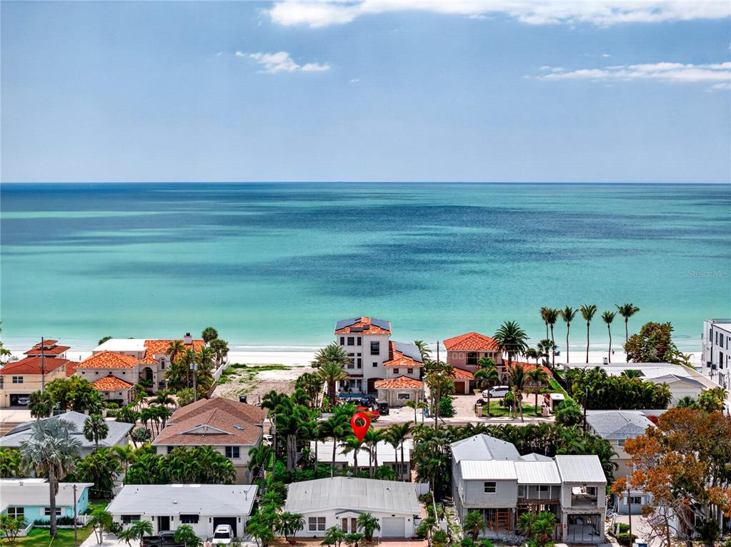 An aerial view shows a coastal neighborhood with houses near a beach and ocean — 16107 GULF BOULEVARD, REDINGTON BEACH, FL