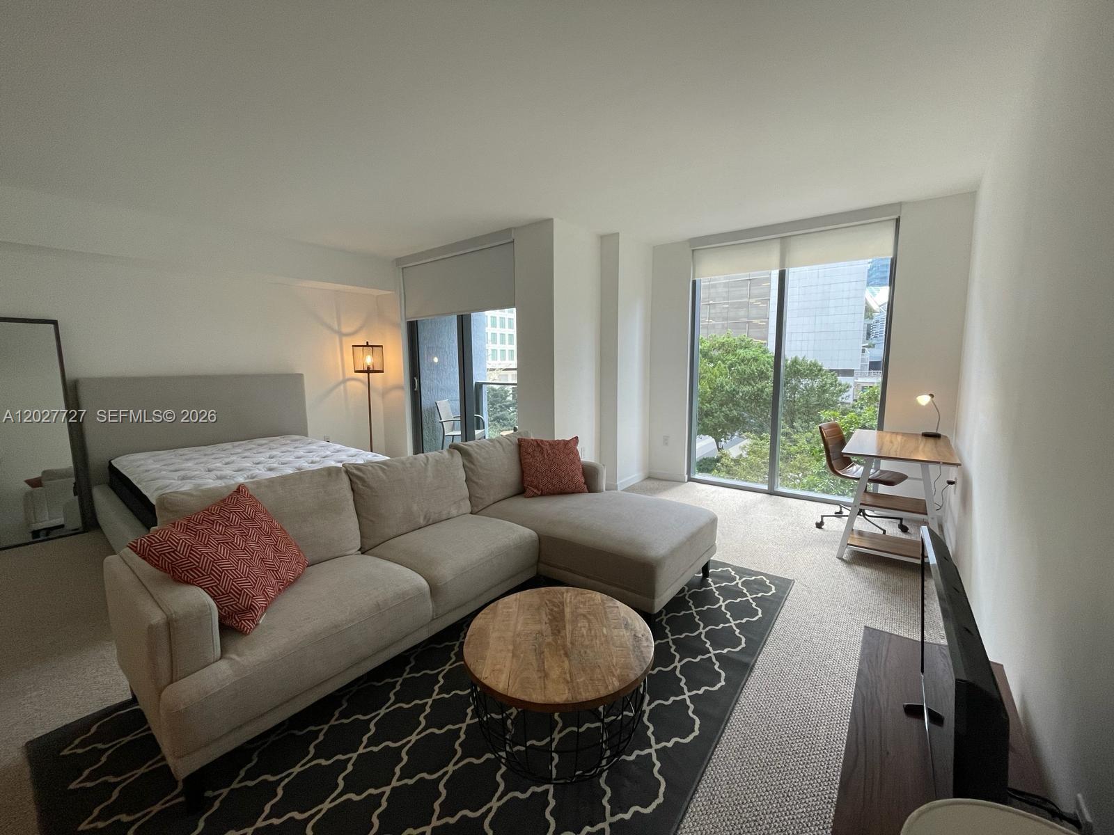A studio apartment features a bed, a sectional sofa, a coffee table, and a desk — 31 SE 6th St # 505, Miami FL 33131, MIAMI, FL