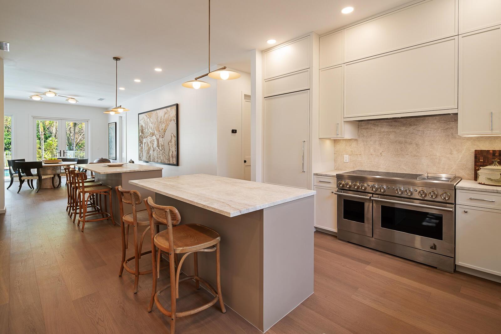 A modern kitchen features two islands, light wood flooring, and stainless steel appliances — 6371 SW 87th Terrace, Pinecrest FL 33156, PINECREST, FL