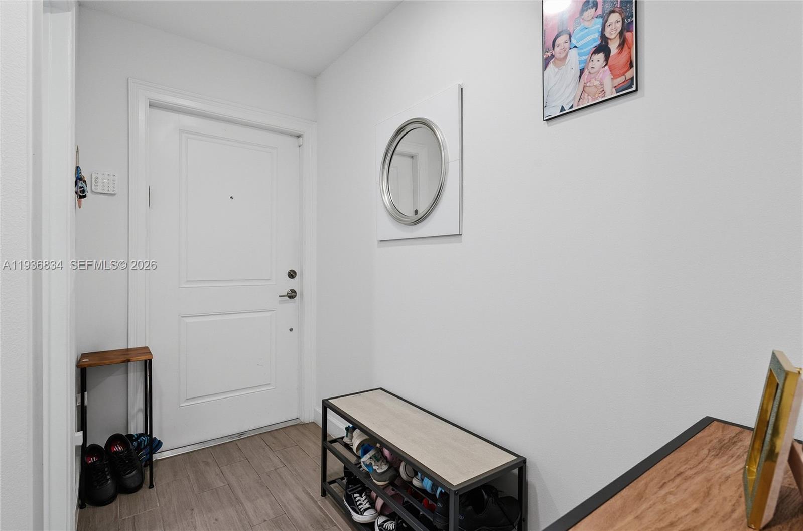 An entryway features a white door, a shoe rack, a small console table, and a mirror — 5059 Genove Pl, Riviera Beach FL 33410, RIVIERA BEACH, FL