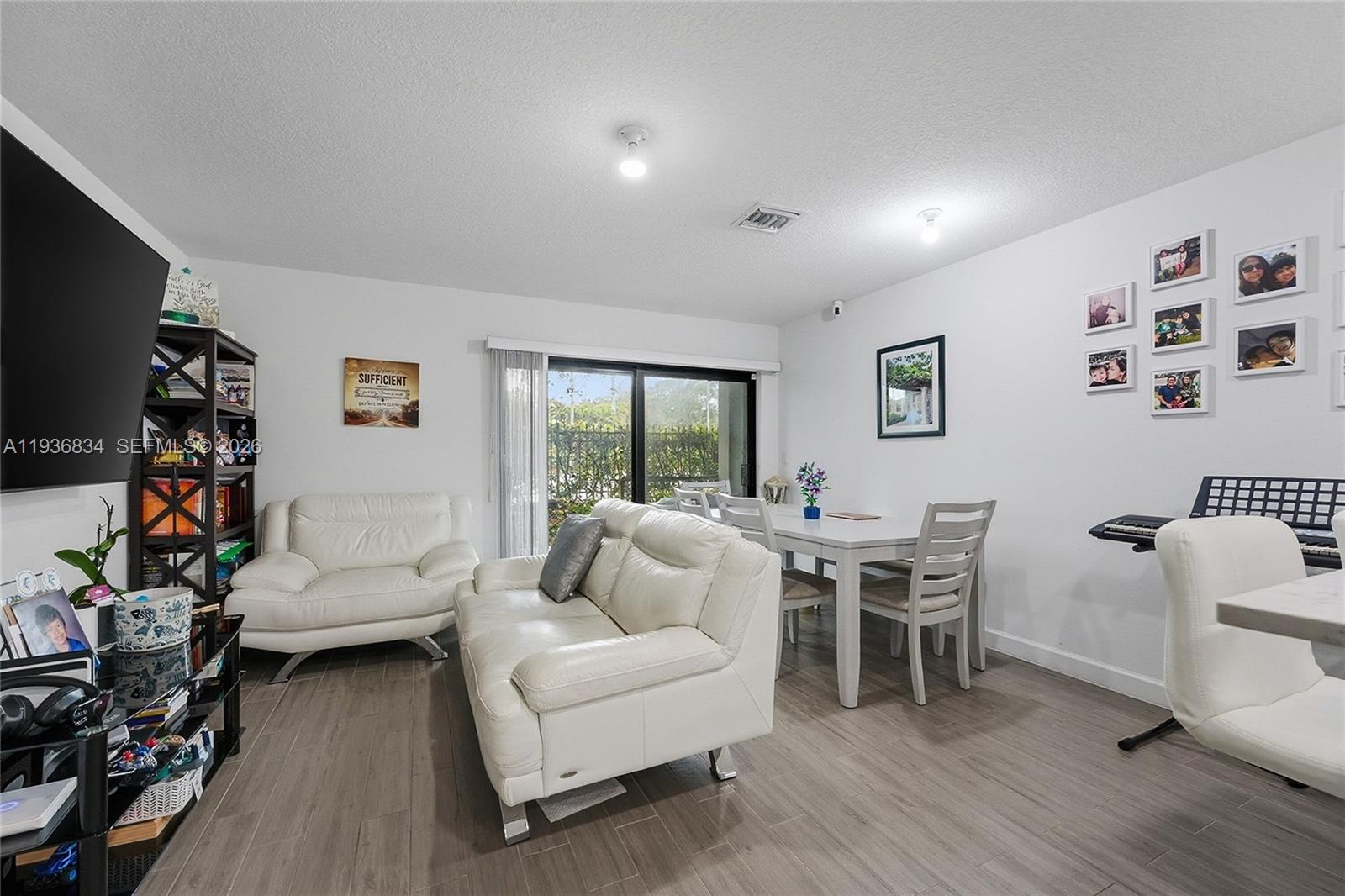 A living and dining area features white leather sofas, a dining set, and wood-look flooring — 5059 Genove Pl, Riviera Beach FL 33410, RIVIERA BEACH, FL