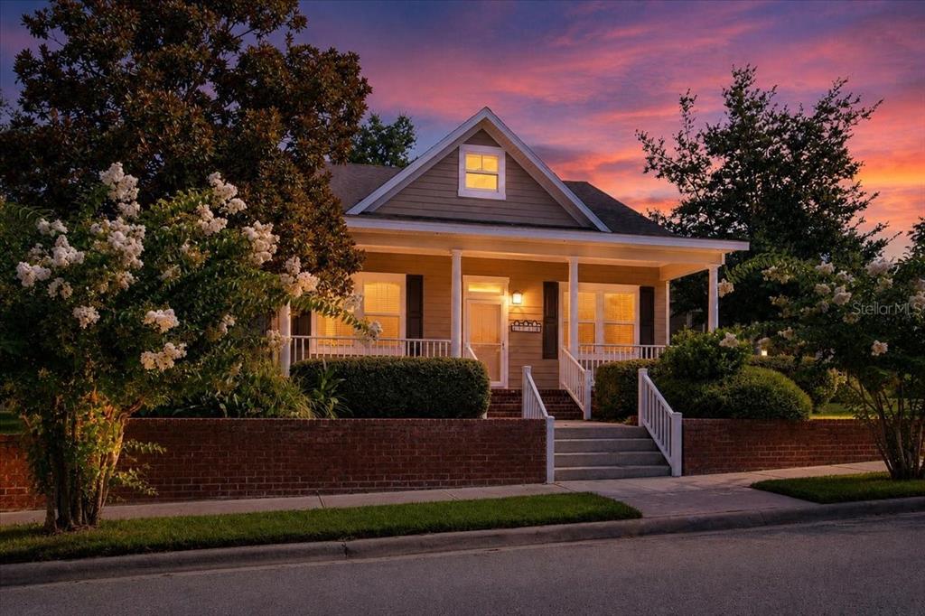 A single-story house with a front porch and brick retaining wall at sunset — 16704 NW 166TH ROAD, ALACHUA, FL