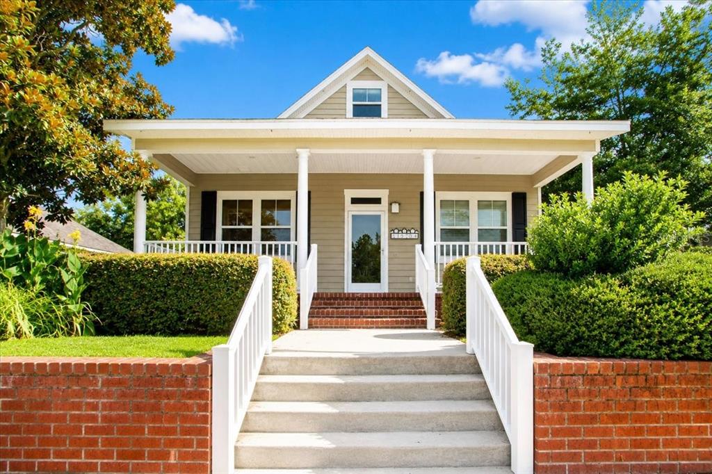 A tan bungalow with a front porch, brick retaining wall, and concrete steps — 16704 NW 166TH ROAD, ALACHUA, FL