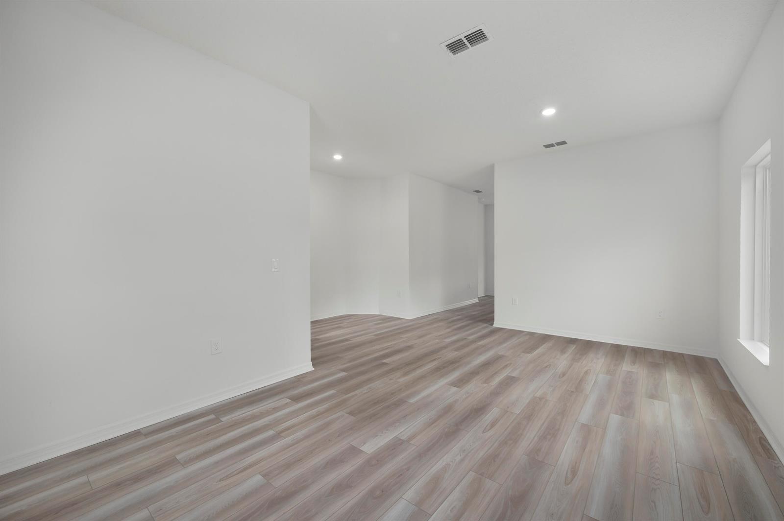 An empty room with white walls, recessed lighting, and light-toned wood-look flooring — 9316 104th Avenue, Vero Beach FL 32967, VERO BEACH, FL