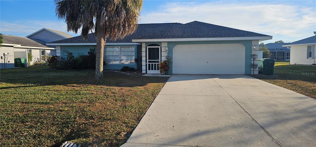A teal, single-story house features a two-car garage, a palm tree, and a concrete driveway — 23077 HAMMOND AVENUE, PORT CHARLOTTE, FL