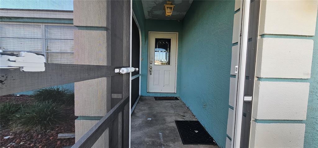 A white front door is visible at the end of a covered concrete entryway — 23077 HAMMOND AVENUE, PORT CHARLOTTE, FL