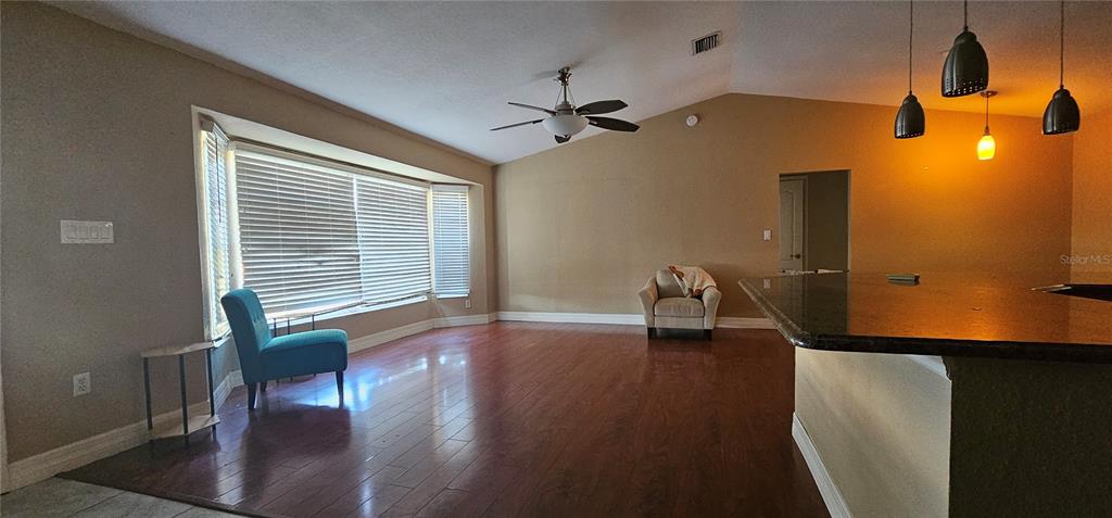 A living room features hardwood floors, a ceiling fan, a bay window, and a kitchen island — 23077 HAMMOND AVENUE, PORT CHARLOTTE, FL