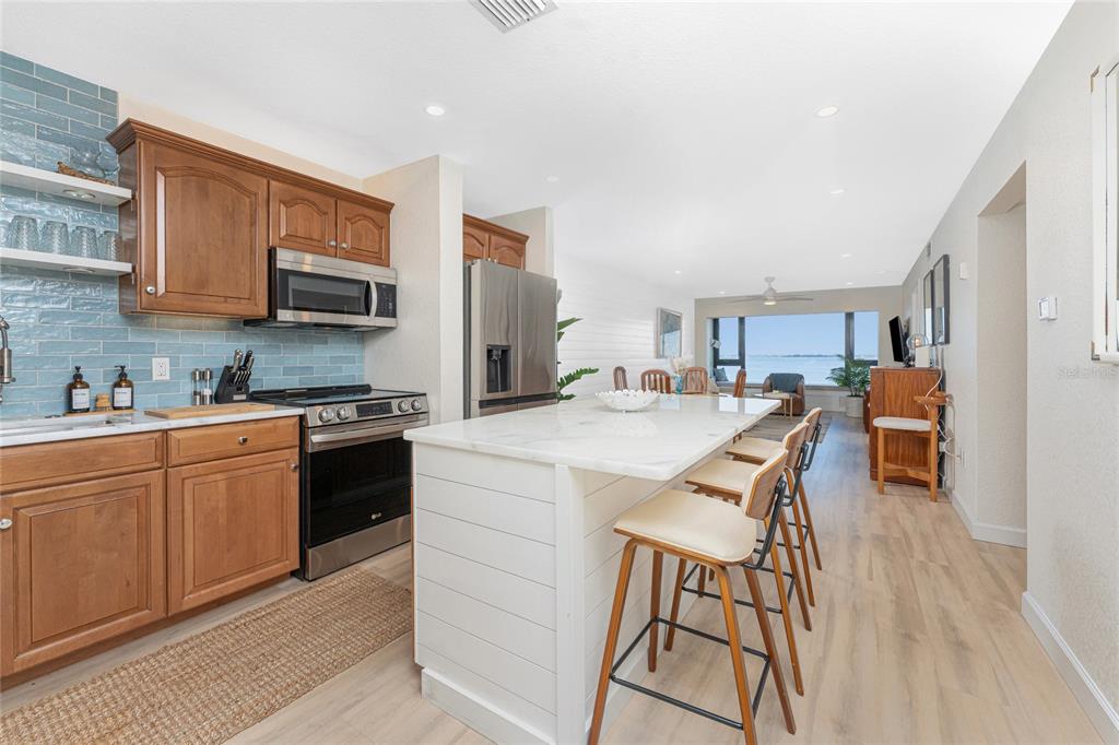 A kitchen with wood cabinets, a white island, and a view of the water — 1500 PARK BEACH CIRCLE UNIT 3D, PUNTA GORDA, FL