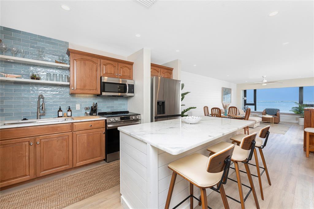 A kitchen features wood cabinets, a blue tiled backsplash, and a white marble island — 1500 PARK BEACH CIRCLE UNIT 3D, PUNTA GORDA, FL