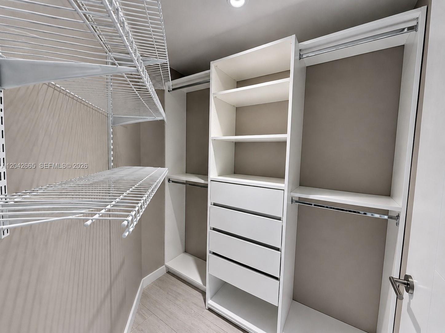A walk-in closet features white shelving, a built-in drawer unit, and wire racks — 1010 SW 2nd Ave # 1809, Miami FL 33130, MIAMI, FL
