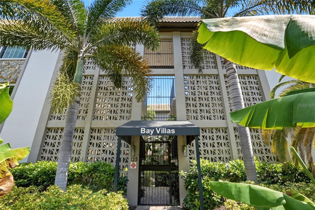 The exterior of a multi-story apartment building features decorative concrete screens and palm trees — 125 5TH AVENUE NE UNIT 210, ST PETERSBURG, FL