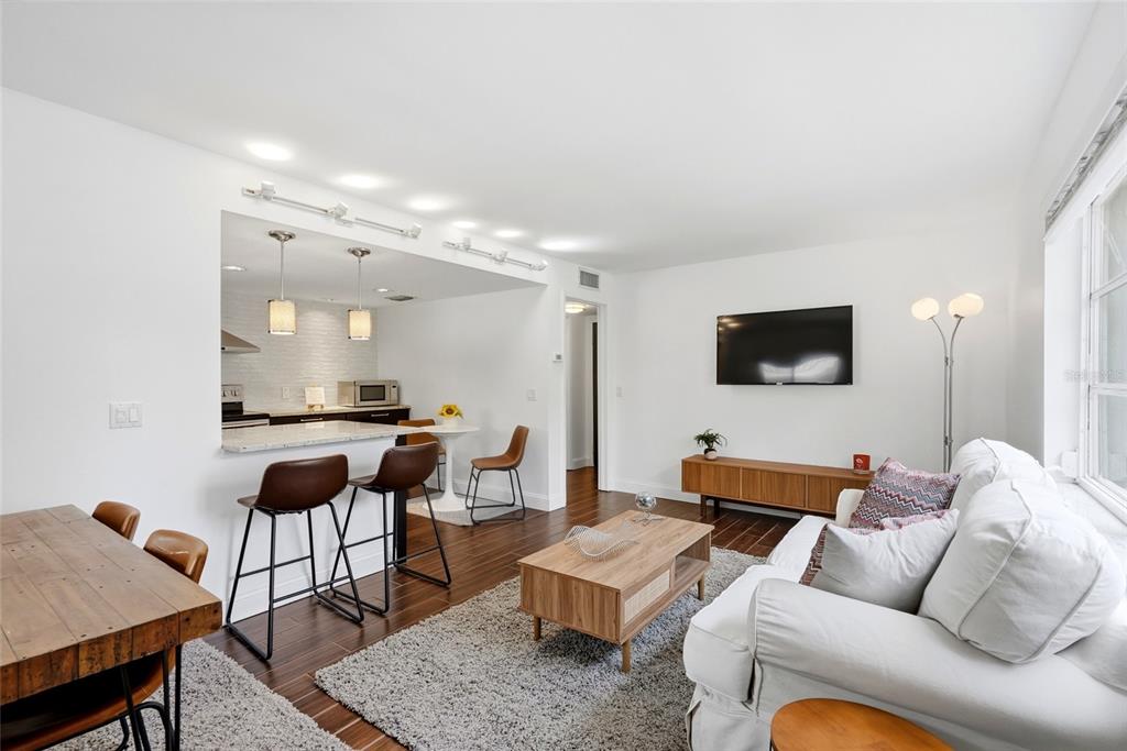 A living room with a white sofa, wood coffee table, and an open kitchen area — 125 5TH AVENUE NE UNIT 210, ST PETERSBURG, FL