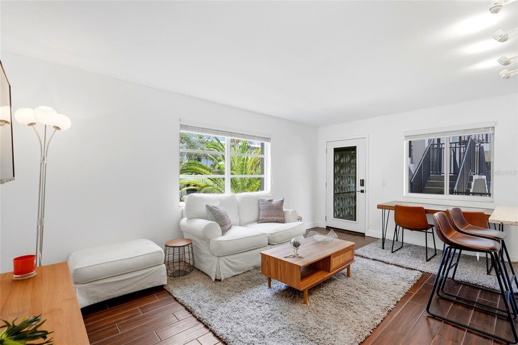 A bright living room features a white sofa, wood coffee table, and a dining area — 125 5TH AVENUE NE UNIT 210, ST PETERSBURG, FL
