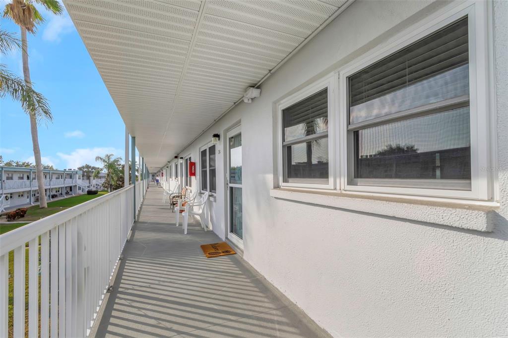 An exterior walkway with white railings runs along the side of a multi-story apartment building — 5246 81ST STREET N UNIT 24, ST PETERSBURG, FL