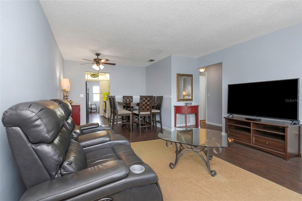 A living room with a leather sofa, glass coffee table, and adjacent dining area — 5246 81ST STREET N UNIT 24, ST PETERSBURG, FL