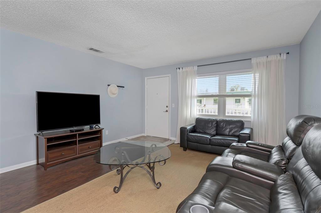 A living room features light blue walls, dark wood flooring, a television, and leather furniture — 5246 81ST STREET N UNIT 24, ST PETERSBURG, FL