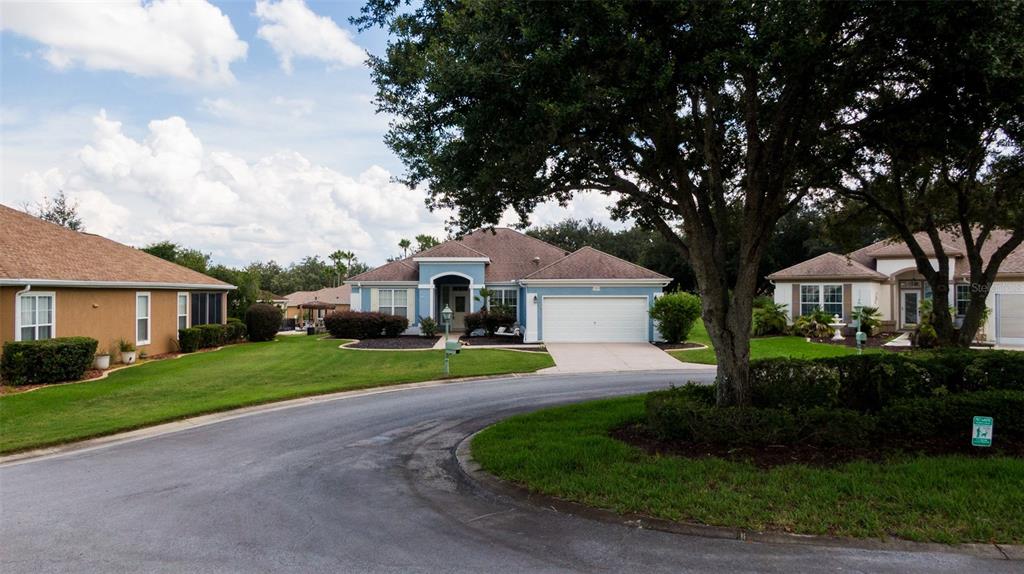 An open-concept living and dining area features gray wood-look flooring and two area rugs — 12855 SE 92ND COURT ROAD, SUMMERFIELD, FL