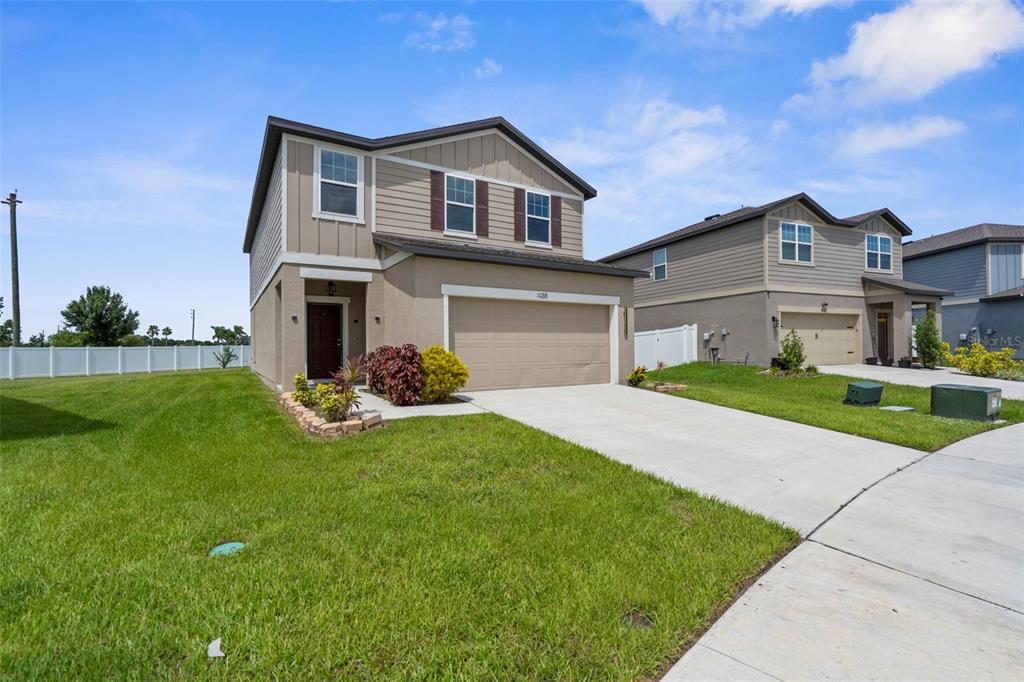A two-story suburban house with a tan stucco and siding exterior and a two-car garage — 1038 KELLY FERN LOOP, RUSKIN, FL