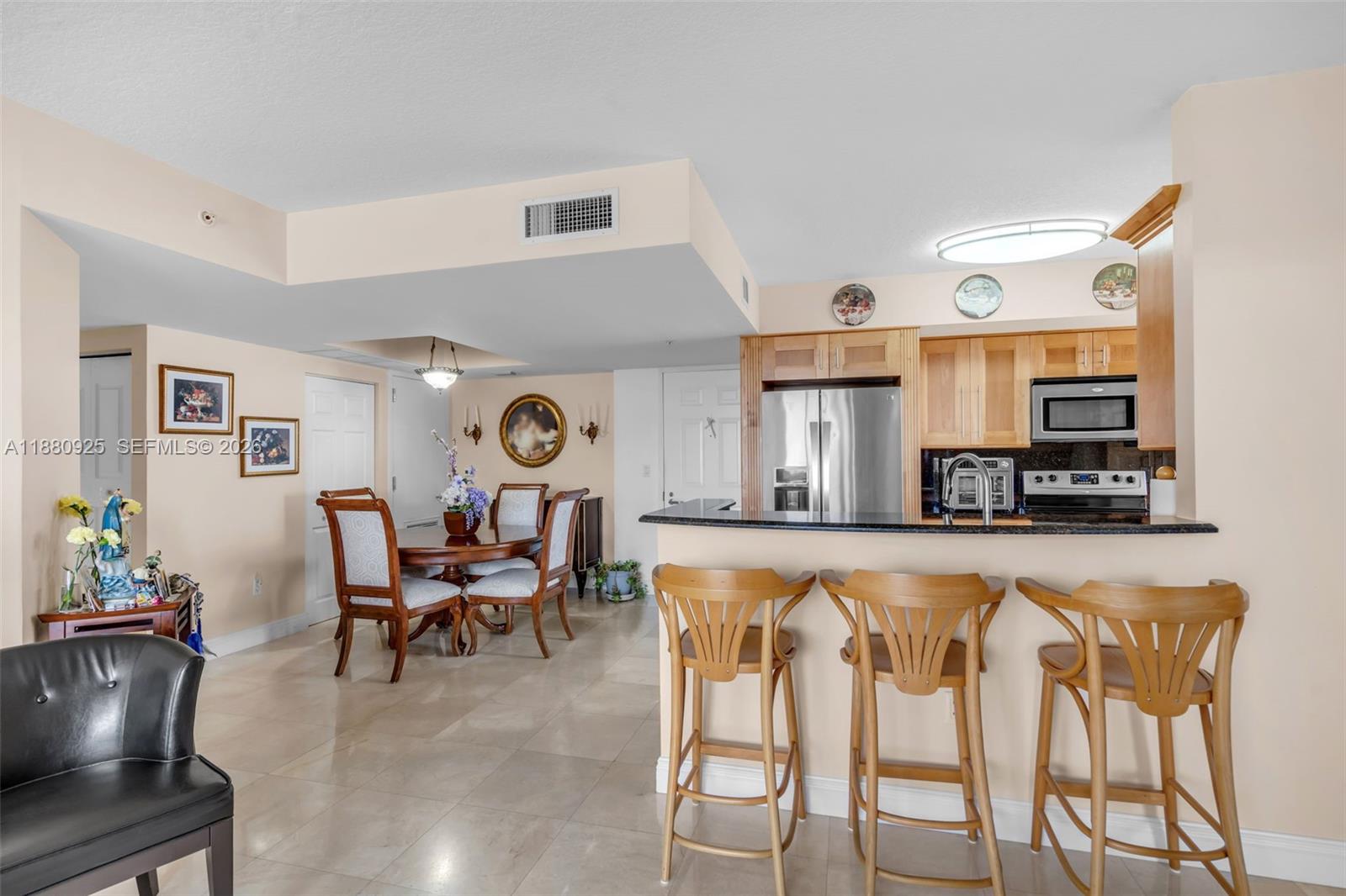 A kitchen with stainless steel appliances and a breakfast bar overlooks a dining area — 3232 SW 22nd Ter # 801, Miami FL 33145, MIAMI, FL
