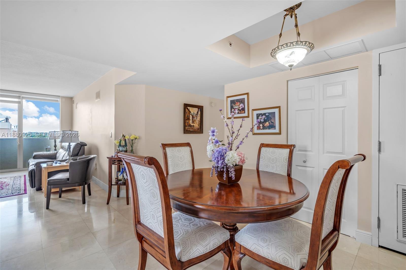 A dining area with a round wooden table and chairs sits adjacent to a living room — 3232 SW 22nd Ter # 801, Miami FL 33145, MIAMI, FL