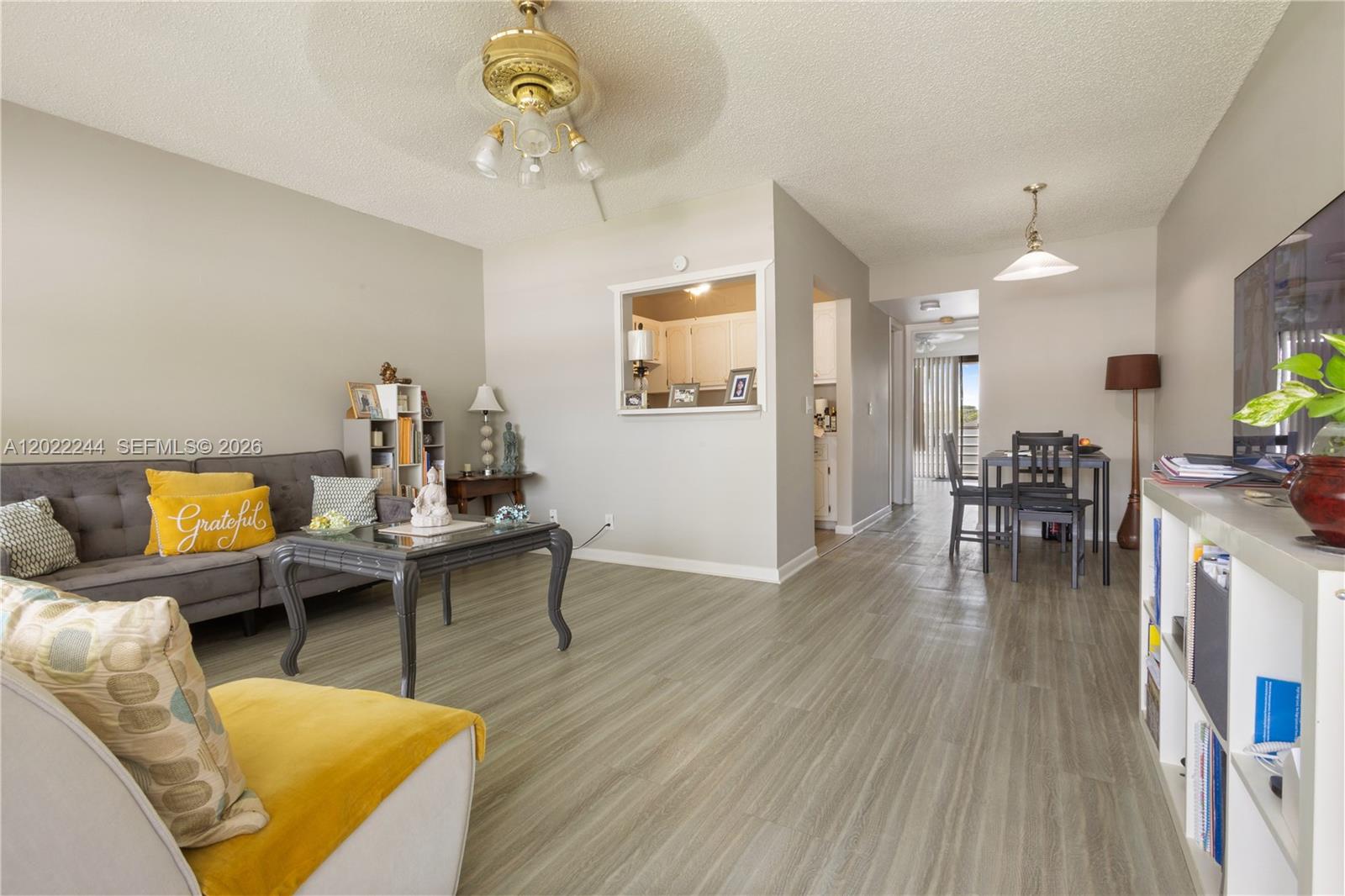 A living room with gray flooring, a gray sofa, a coffee table, and a dining area — 75 Ventnor D # 75, Deerfield Beach FL 33442, DEERFIELD BEACH, FL