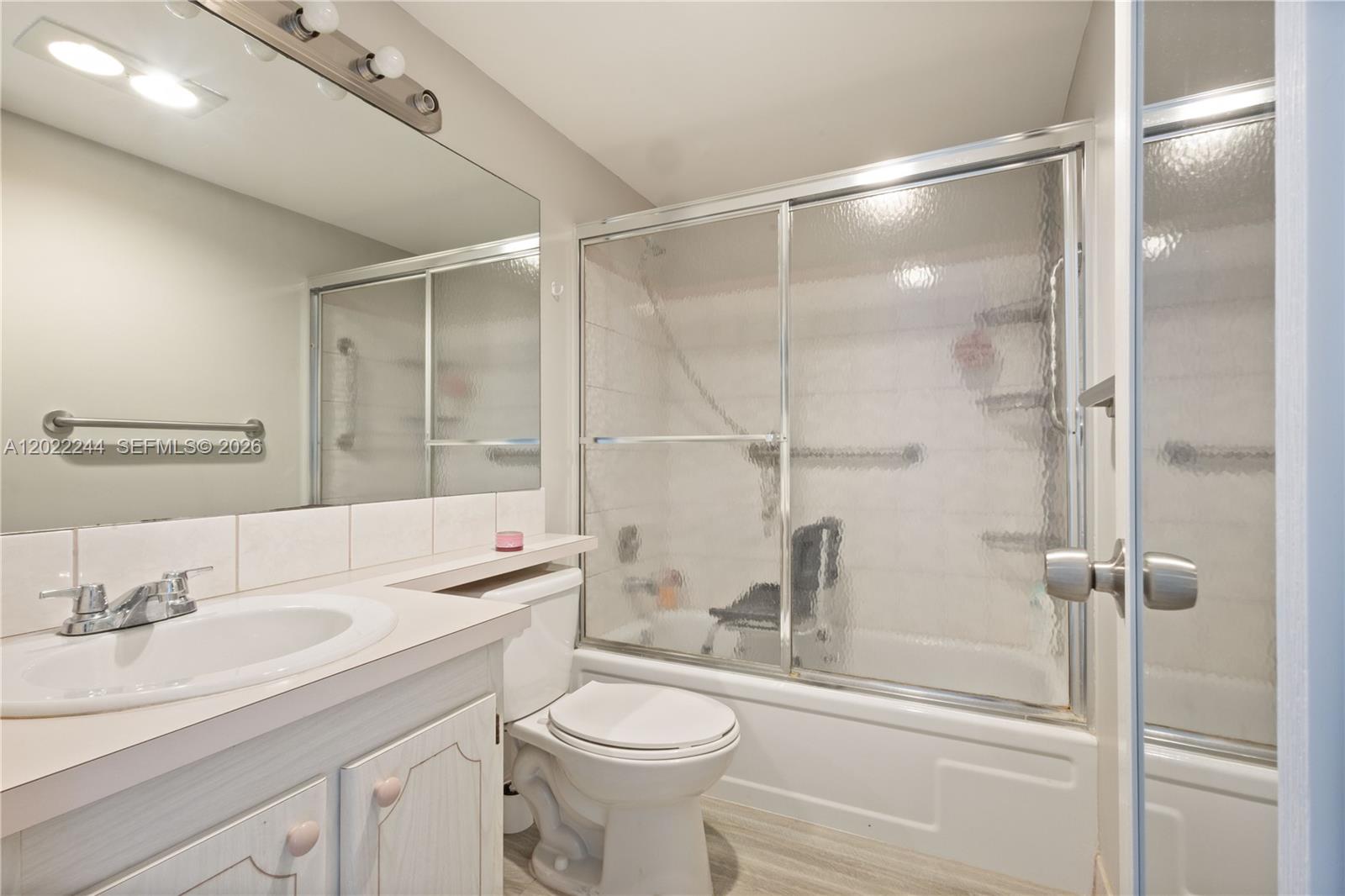 A bathroom features a white vanity, a toilet, and a shower-tub combo with sliding doors — 75 Ventnor D # 75, Deerfield Beach FL 33442, DEERFIELD BEACH, FL