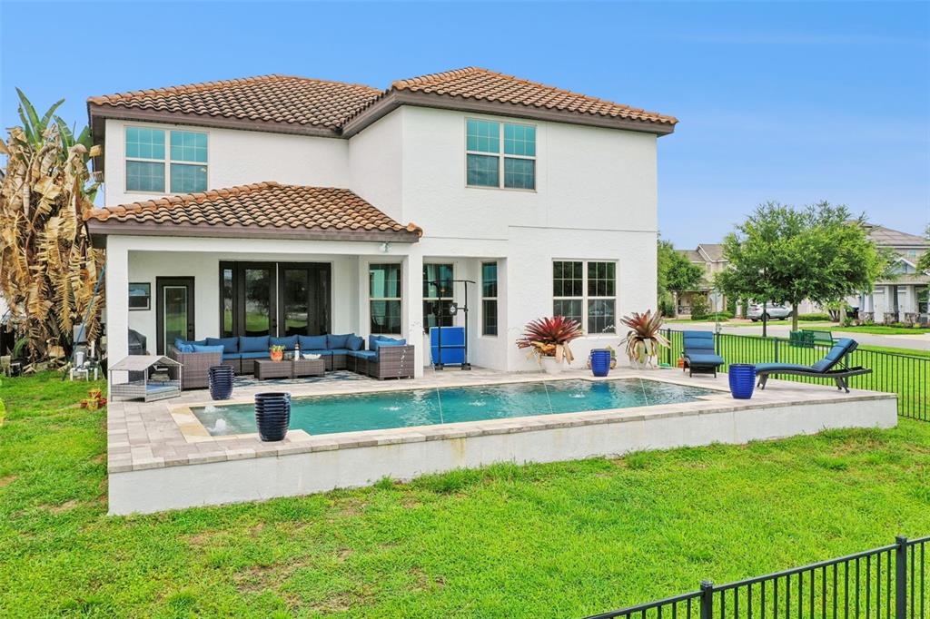 A two-story house features a backyard swimming pool with a patio and outdoor seating area — 9189 BUSACO PARK WAY, WINTER GARDEN, FL