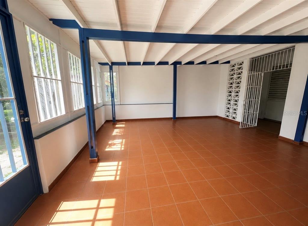 An open-air patio features terracotta tile flooring, white walls, and blue structural support beams — Circulo C CASA EN RAMEY UNIT 213-A, AGUADILLA, PR
