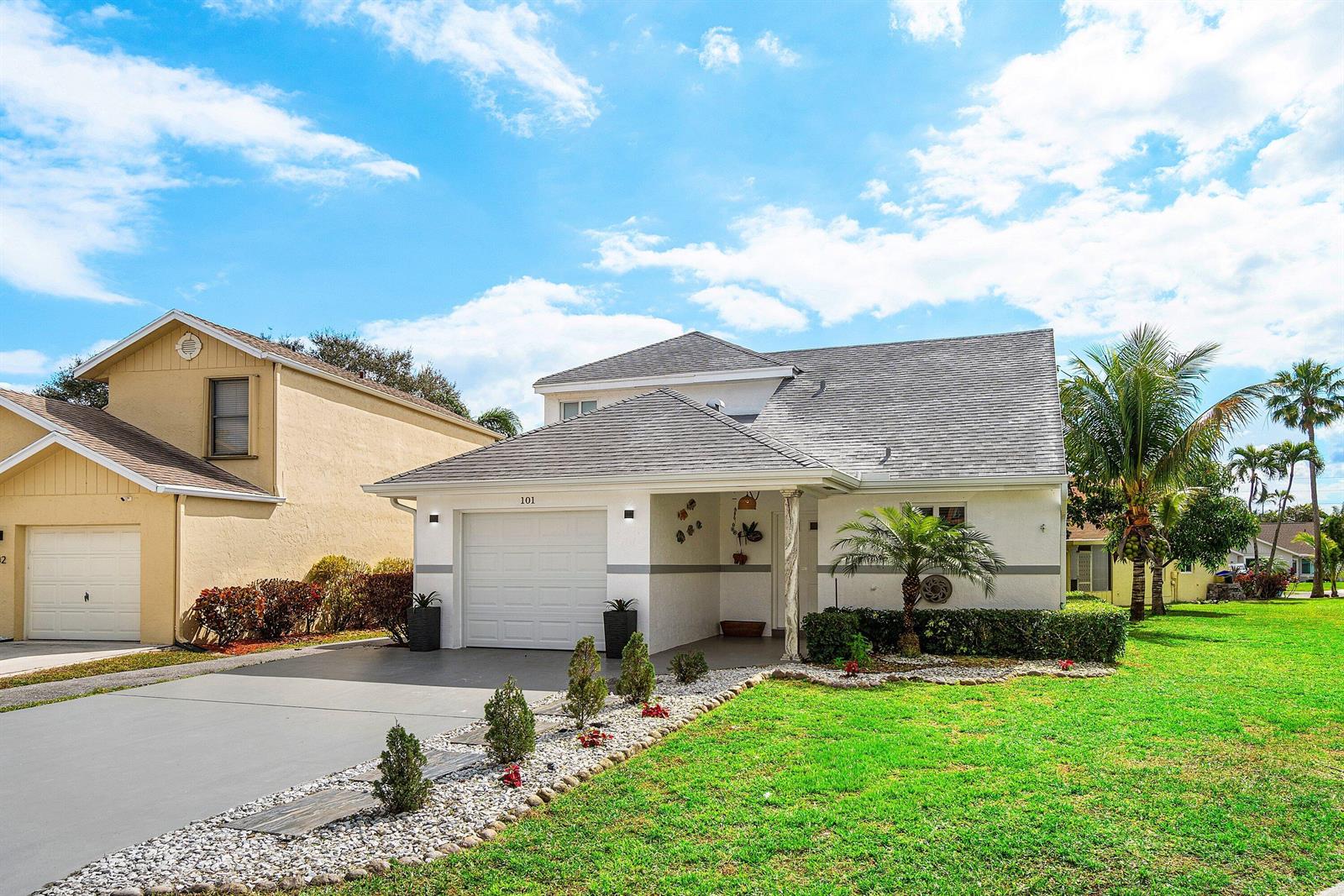 A white house with a gray roof and a concrete driveway under a blue sky — 101 Azalea Circle, Boynton Beach FL 33436, BOYNTON BEACH, FL