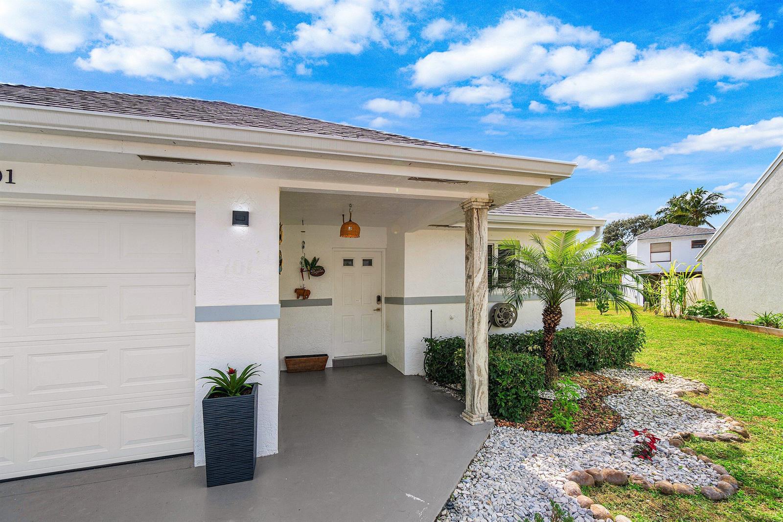A white house exterior features a garage, a covered entryway, and a landscaped front yard — 101 Azalea Circle, Boynton Beach FL 33436, BOYNTON BEACH, FL