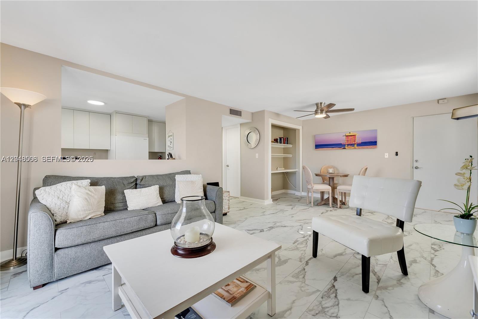 A living room features a gray sofa, white coffee table, dining area, and marble flooring — 1418 Collins Ave # 504, Miami Beach FL 33139, MIAMI BEACH, FL