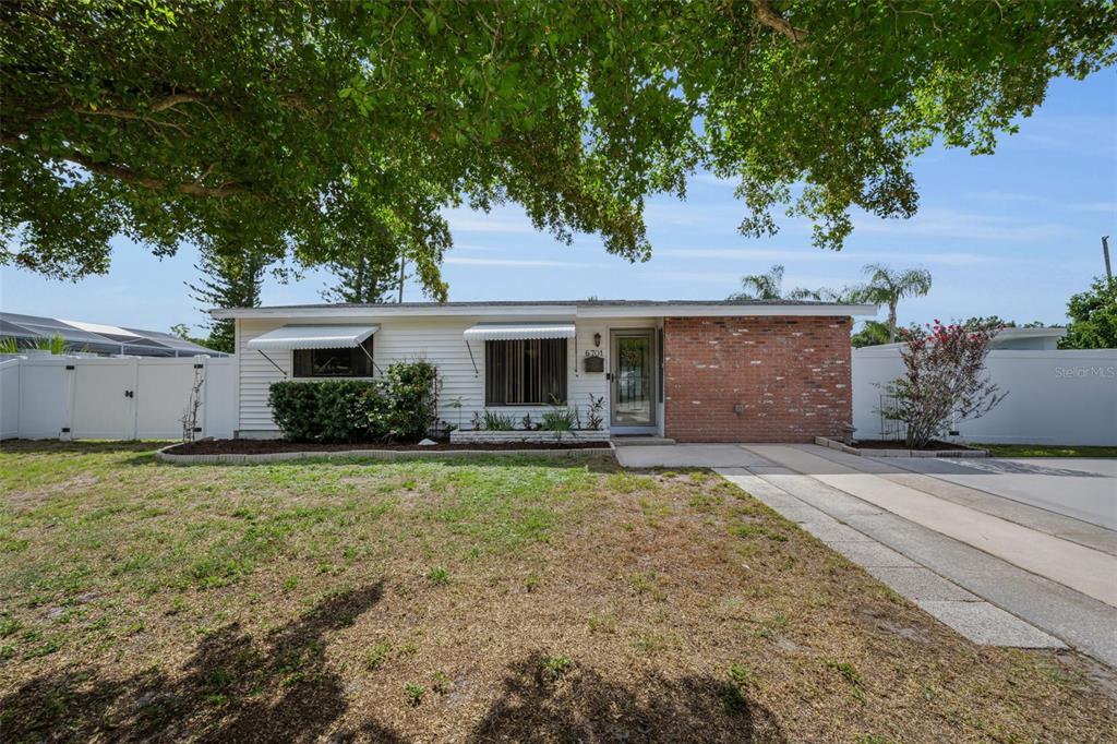 A single-story house with white siding, a brick facade, and a concrete driveway — 6701 ORCHARD DRIVE N, ST PETERSBURG, FL