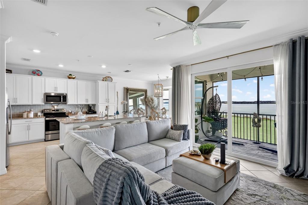 A living room features a gray accent wall, a sectional sofa, and a balcony view — 43050 GREENWAY BOULEVARD UNIT 645, PUNTA GORDA, FL