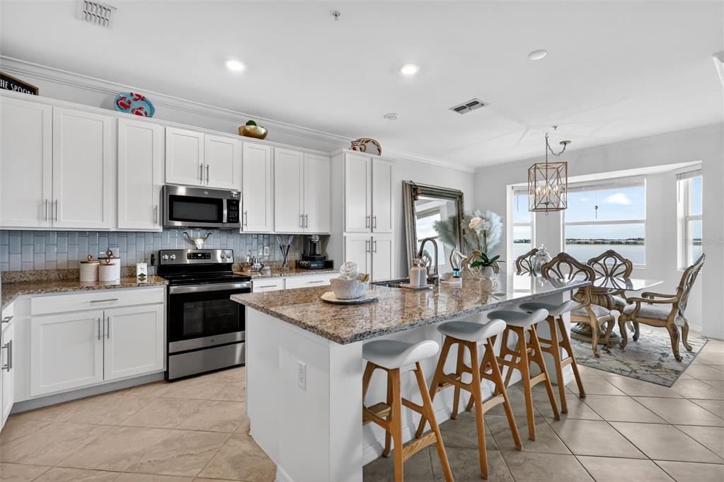 An open-concept kitchen and living area features granite countertops, bar seating, and a water view — 43050 GREENWAY BOULEVARD UNIT 645, PUNTA GORDA, FL