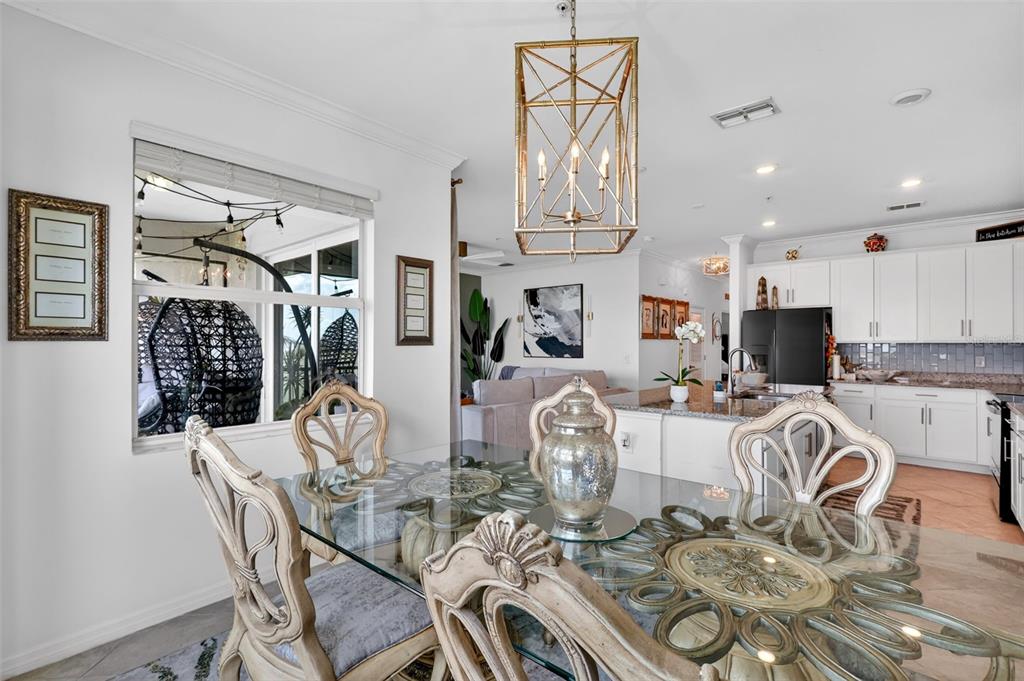 A kitchen features white cabinets, granite countertops, a central island with four stools, and stainless appliances — 43050 GREENWAY BOULEVARD UNIT 645, PUNTA GORDA, FL