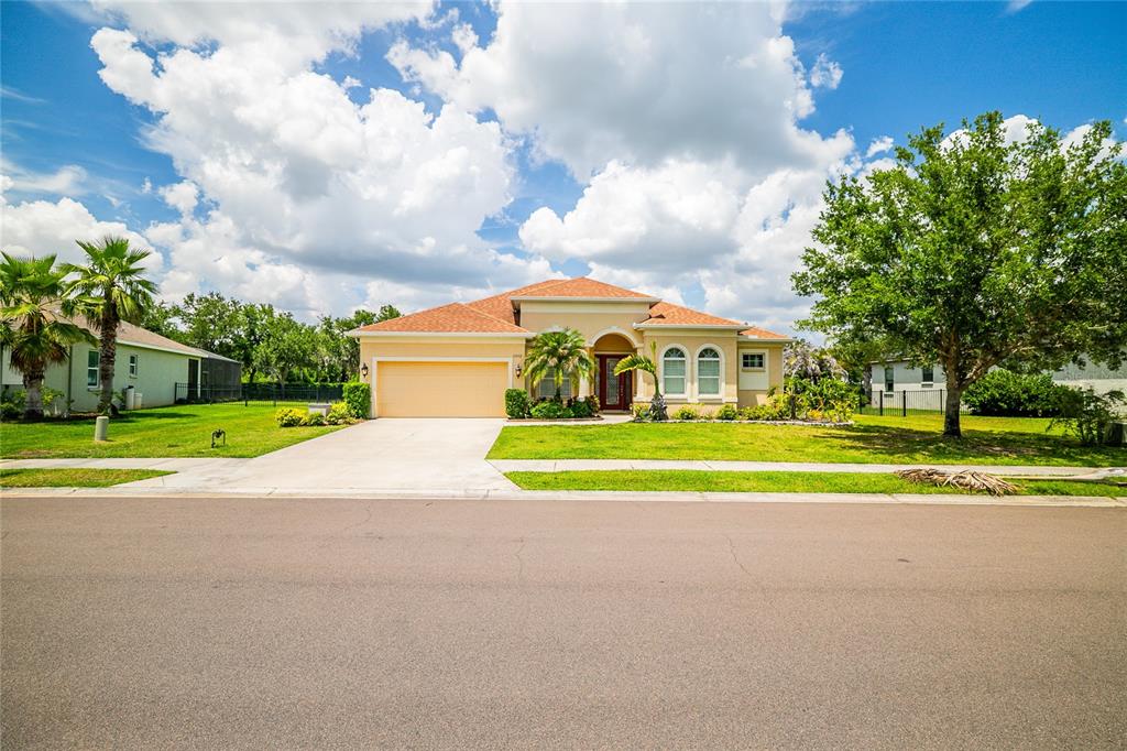 A single-story suburban house with a tan exterior, orange roof, and a concrete driveway — 13502 22ND COURT E, PARRISH, FL
