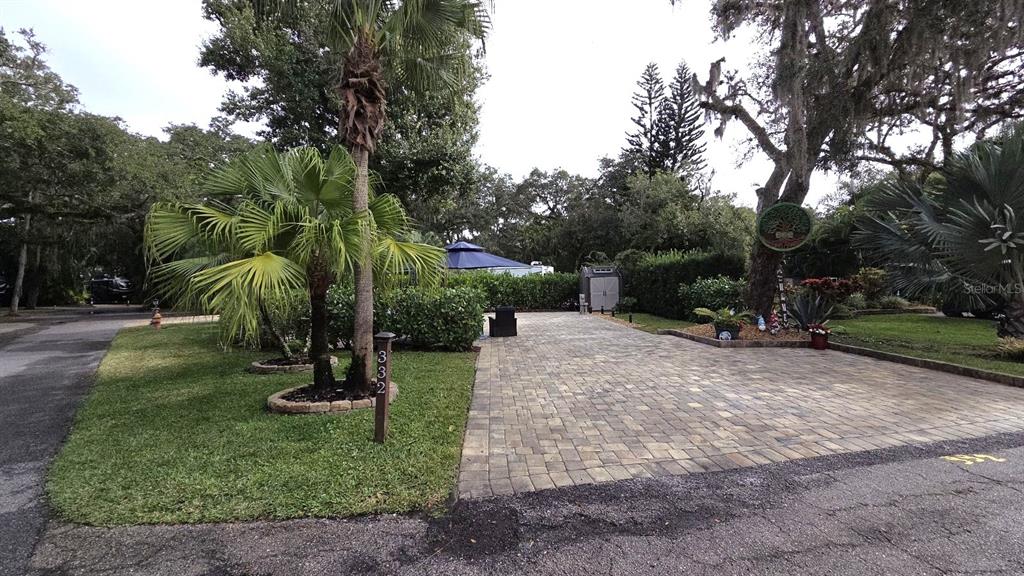 A paved driveway leads to a landscaped lot with a palm tree and small shed — 332 BOBCAT LANE, LAKE WALES, FL