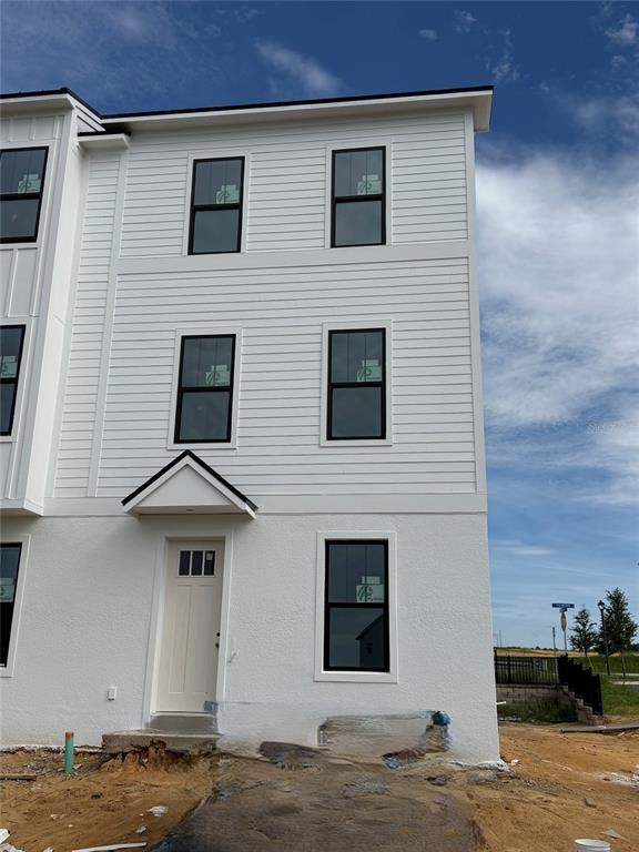 A three-story white townhouse exterior features black-framed windows and a small covered entryway — 15111 GROVESIDE ROAD, WINTER GARDEN, FL