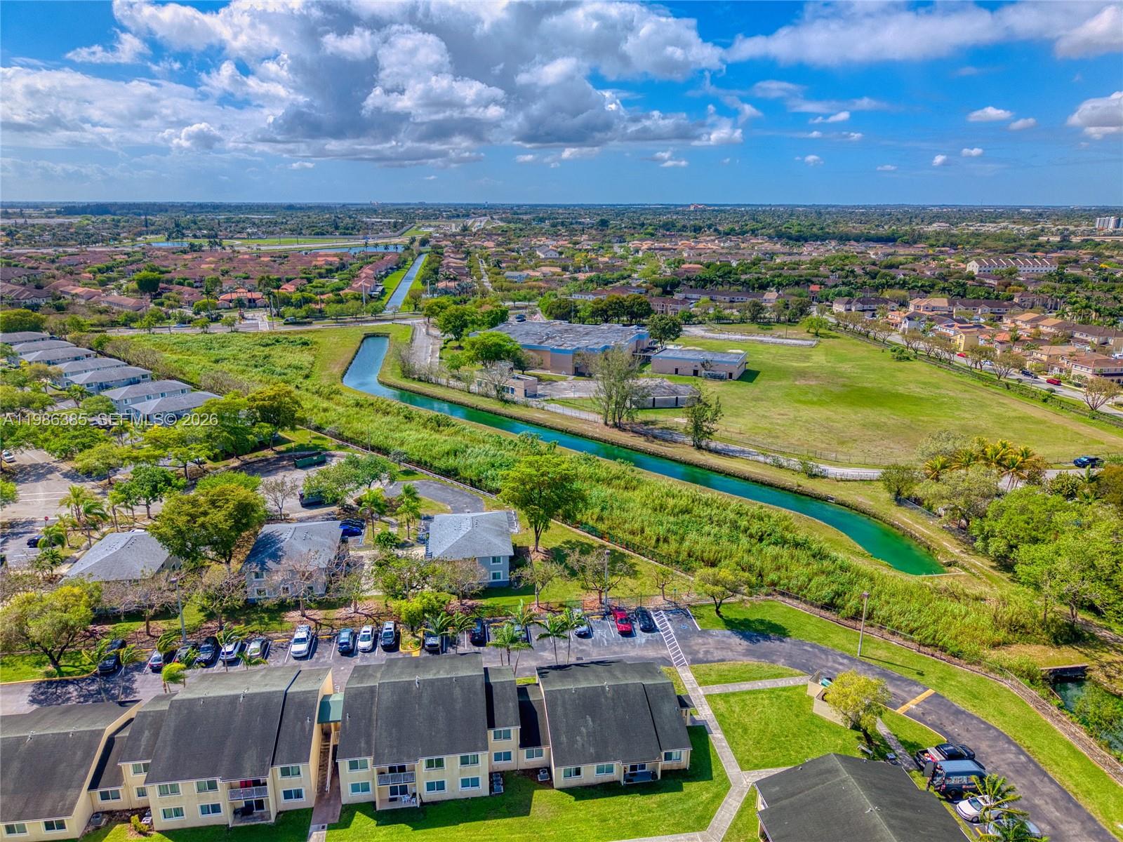 An aerial view shows a residential complex with a canal and surrounding suburban landscape — 139XX SW 272 ST, Naranja FL 33032, NARANJA, FL