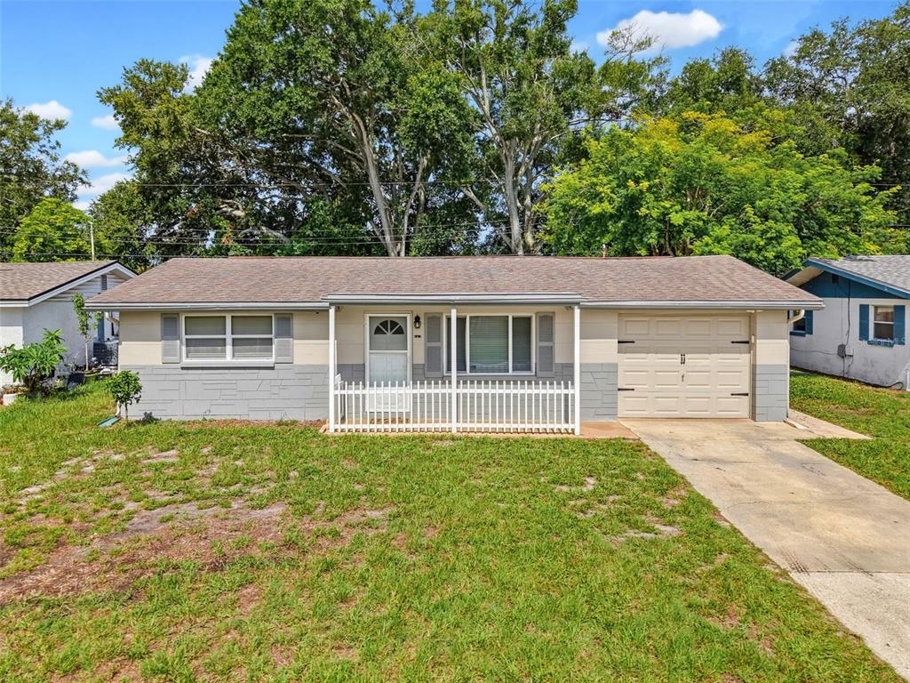 A single-story house with a beige and gray exterior, a front porch, and an attached garage — 4737 BELFAST DRIVE, NEW PORT RICHEY, FL