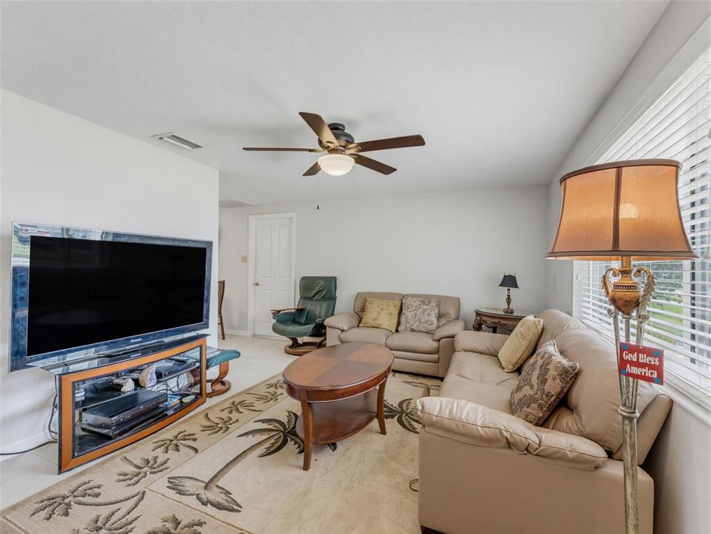 A living room features a television, leather sofa, armchair, coffee table, and a ceiling fan — 4737 BELFAST DRIVE, NEW PORT RICHEY, FL