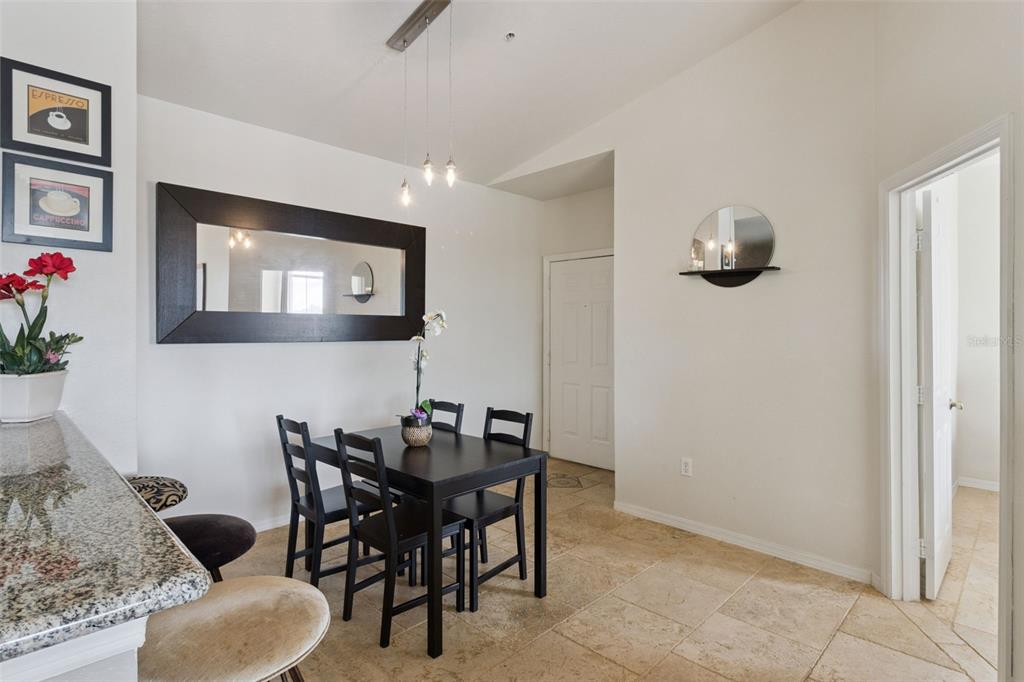 A dining area features a dark wood table, four chairs, a large mirror, and tile flooring — 8811 DUNES COURT UNIT 308, KISSIMMEE, FL
