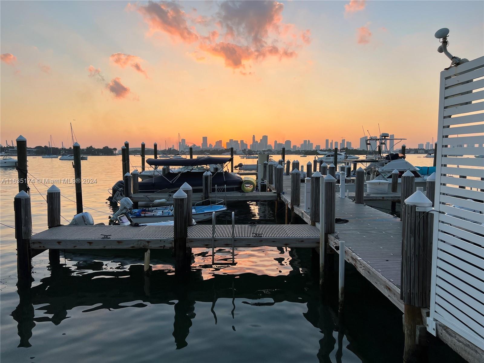 A wooden boat dock extends into the water toward a city skyline at sunset — 1500 Bay Rd # 522S, Miami Beach FL 33139, MIAMI BEACH, FL