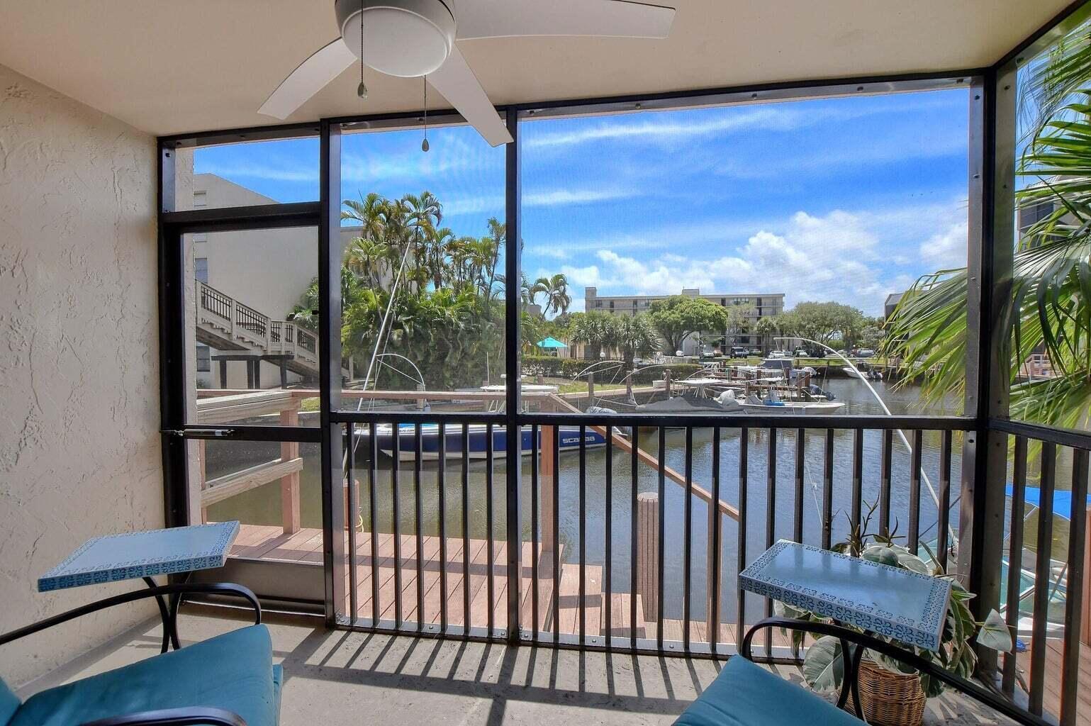 A screened-in balcony overlooks a canal with docked boats and palm trees — 3 Royal Palm Way # 102, Boca Raton FL 33432, BOCA RATON, FL