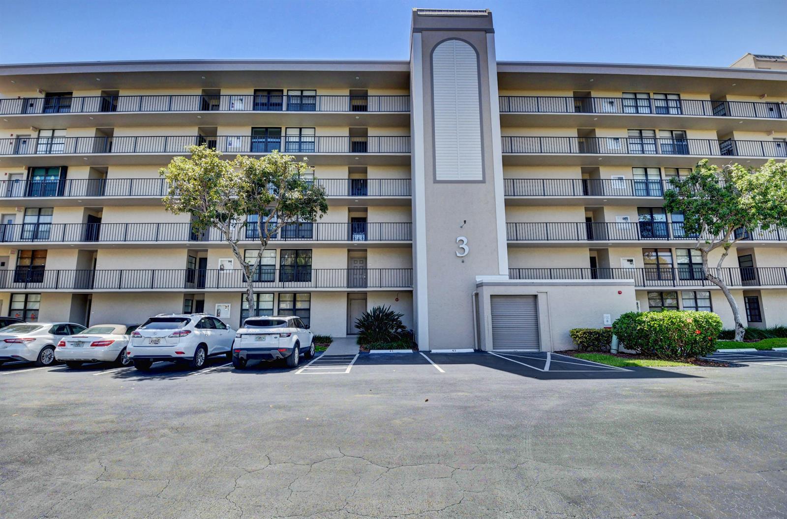 A multi-story apartment building with balconies and a parking lot in the foreground — 3 Royal Palm Way # 102, Boca Raton FL 33432, BOCA RATON, FL