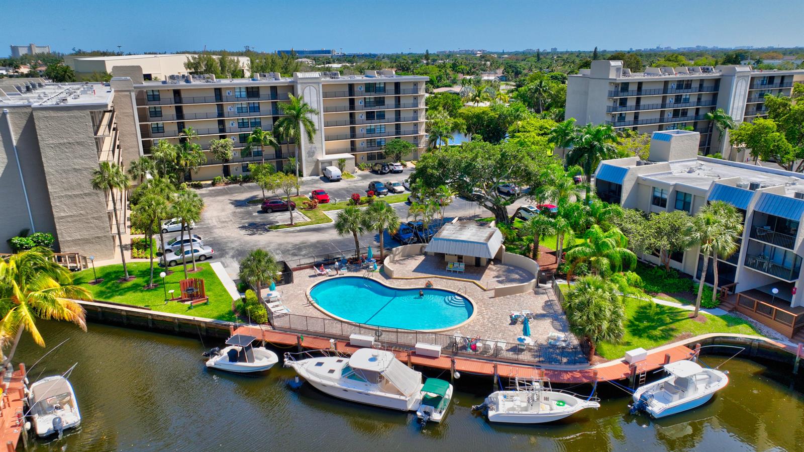An aerial view of a waterfront apartment complex with a swimming pool and docked boats — 3 Royal Palm Way # 102, Boca Raton FL 33432, BOCA RATON, FL
