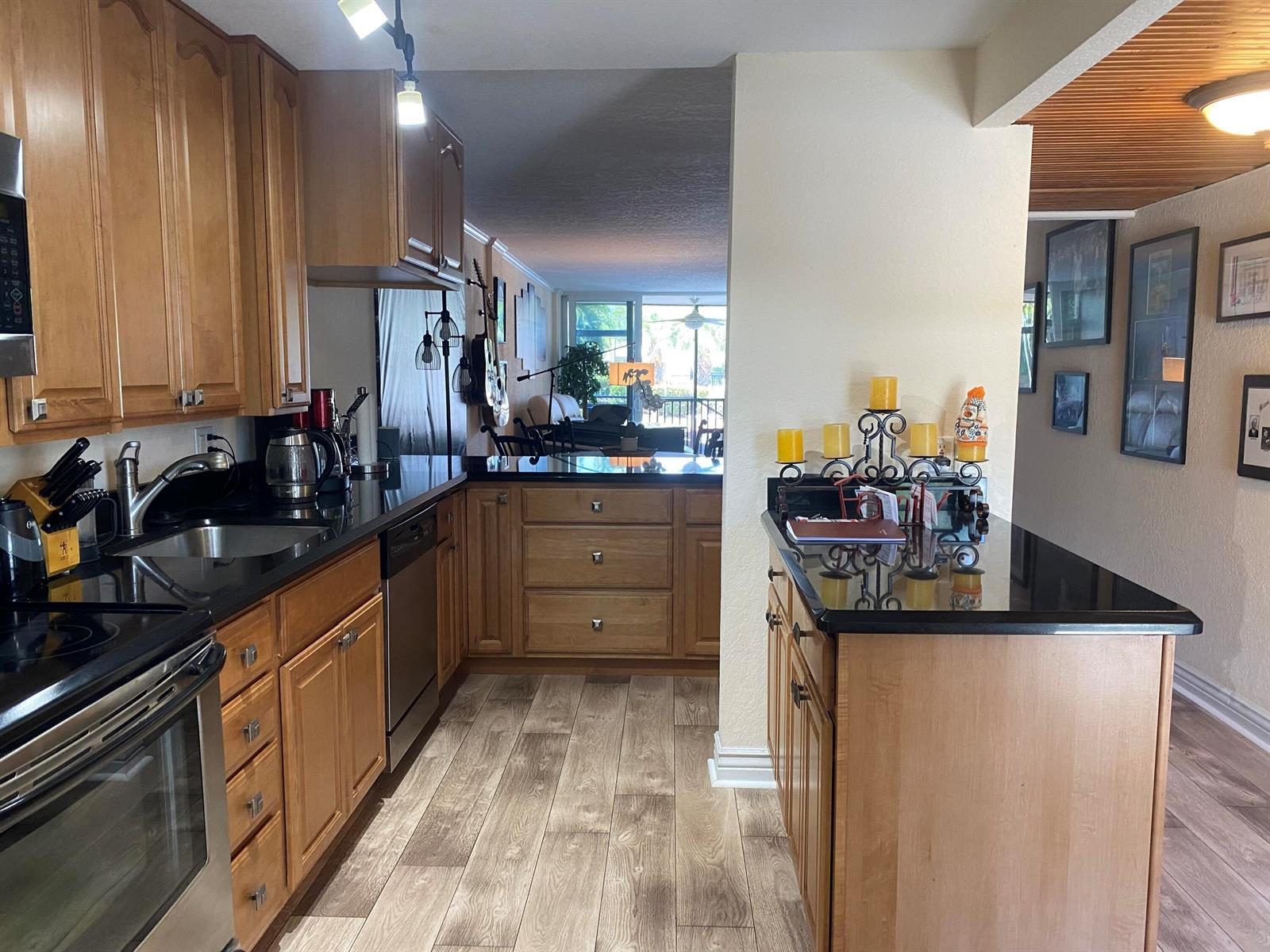 A kitchen features wood cabinets, black countertops, stainless steel appliances, and wood-look flooring — 3 Royal Palm Way # 102, Boca Raton FL 33432, BOCA RATON, FL