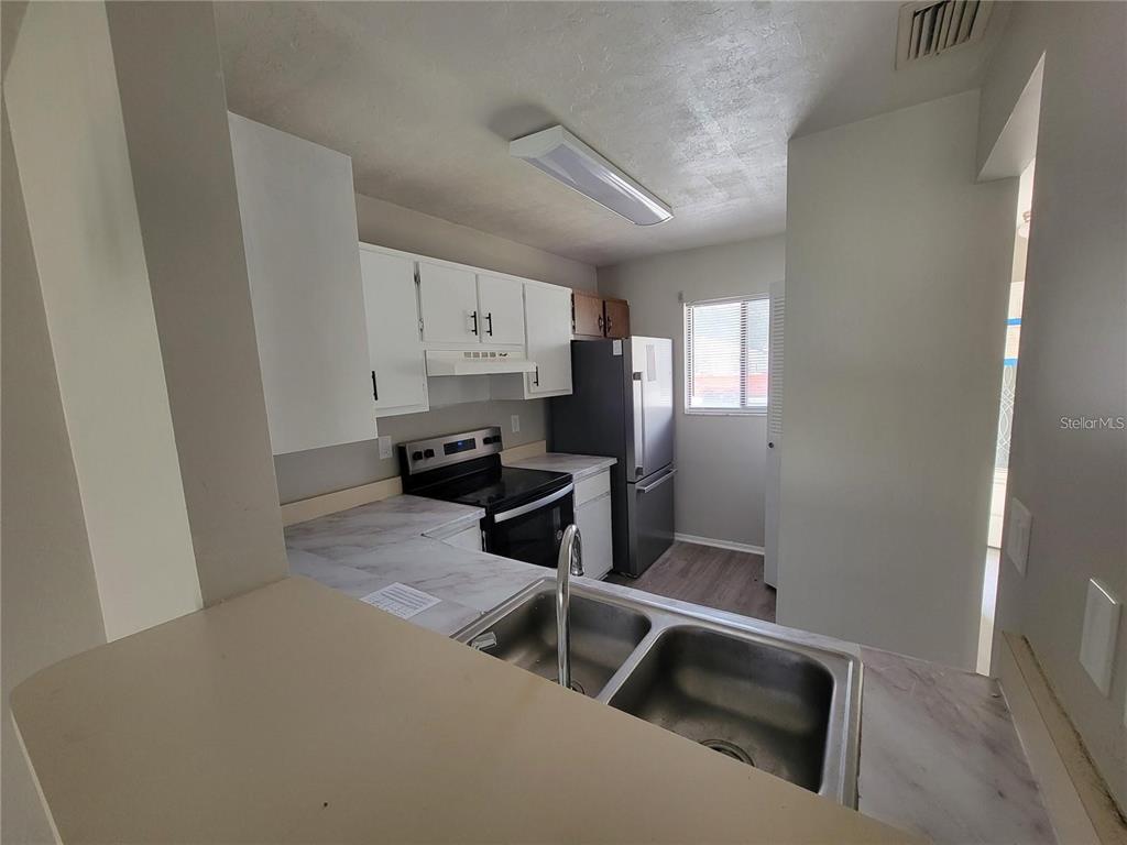 A kitchen features white cabinets, a stainless steel refrigerator, a stove, and a double sink — 3625 NE 20TH PLACE, OCALA, FL